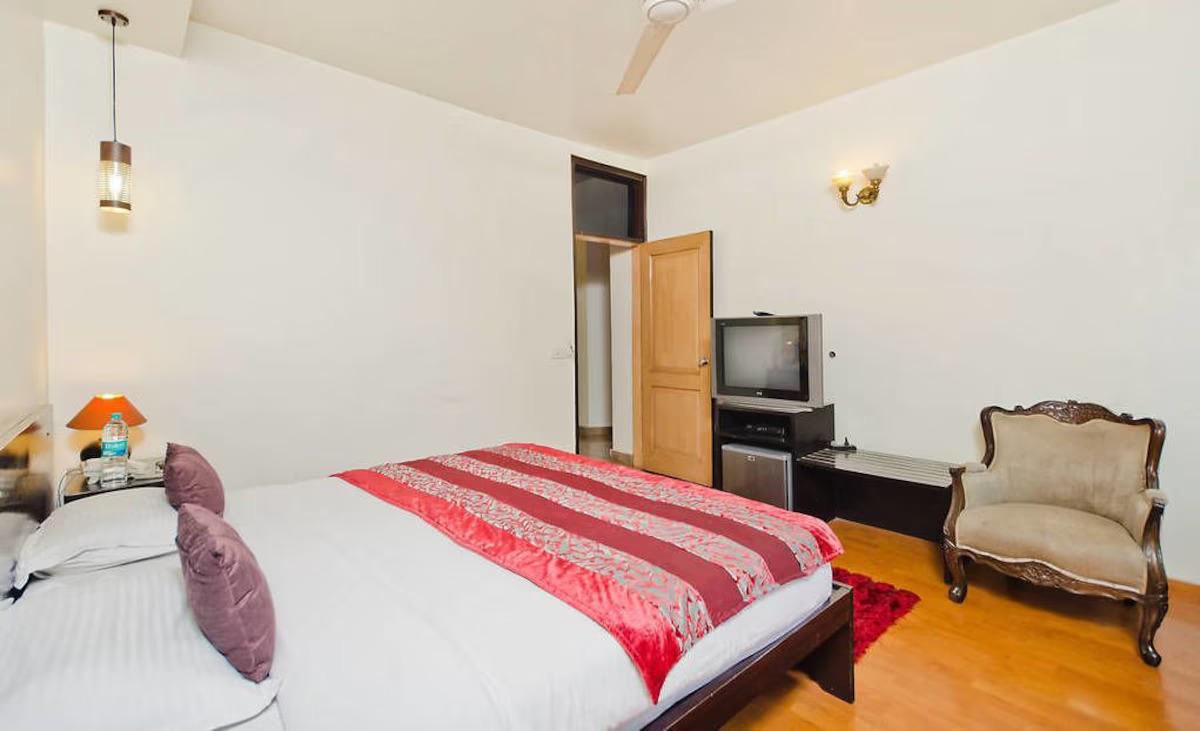 bed room with t.v with sofa at grand ffour new delhi hotel_Image