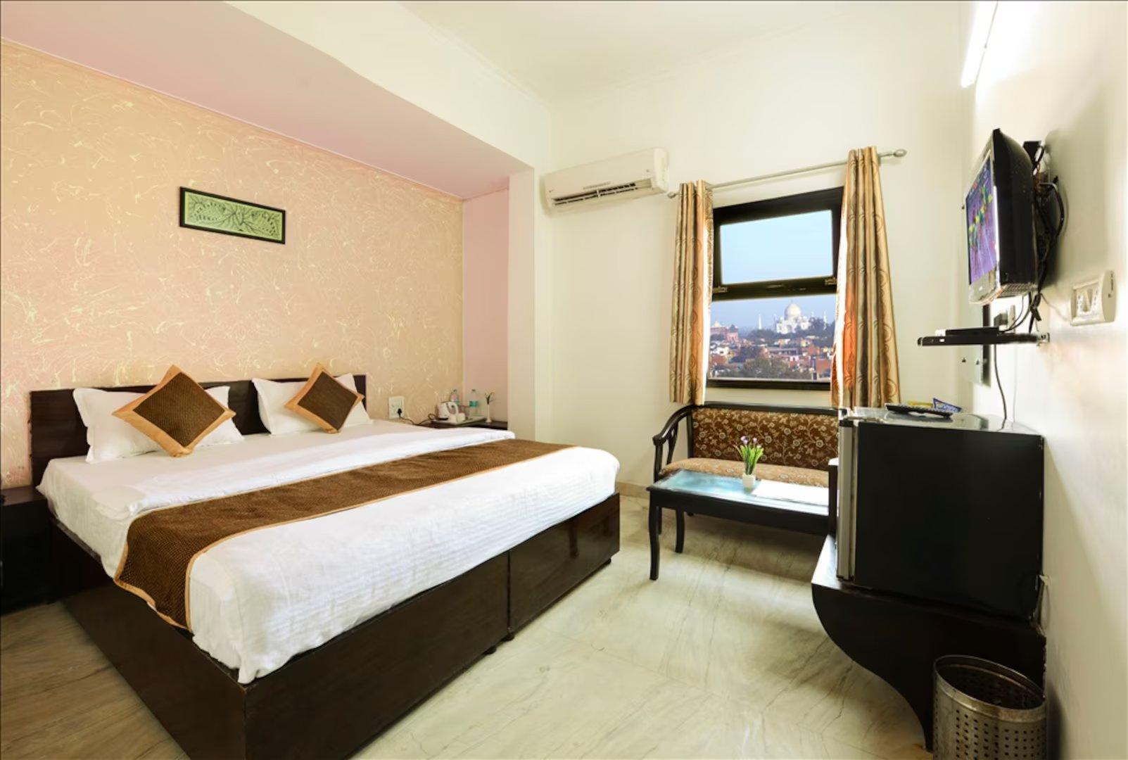 a bedroom with a large bed and a tv at hotel the first by goyal hoteliers in Aagra hotel_Image