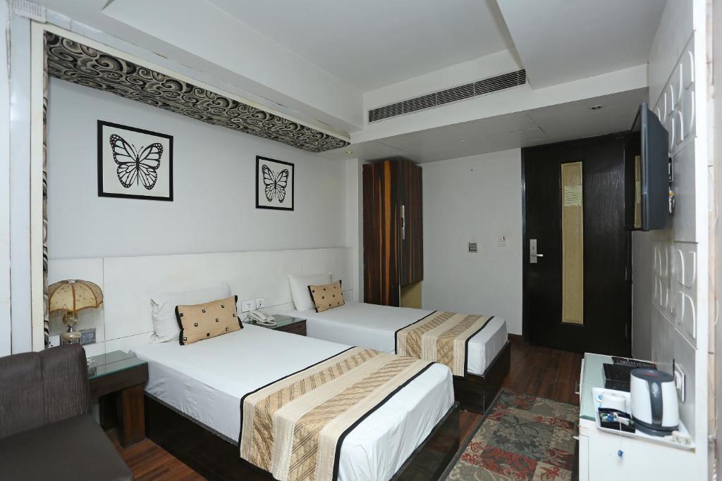 a bedroom with two single bed and a table at hotel uppal international in new delhi hotel_Image