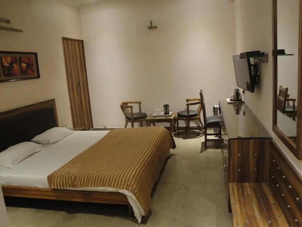 a bedroom with a tv and sofa at The Urmi hotel in Haridwar hotel_Image