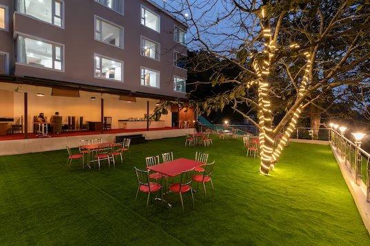 a garden area with tables and chairs at staybook hotel wild wood in mussoorie hotel_Image