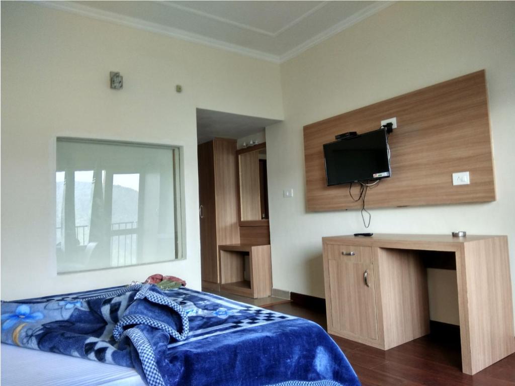 a bedroom with a large bed and a tvat hotel emerald valley in Chail hotel_Image