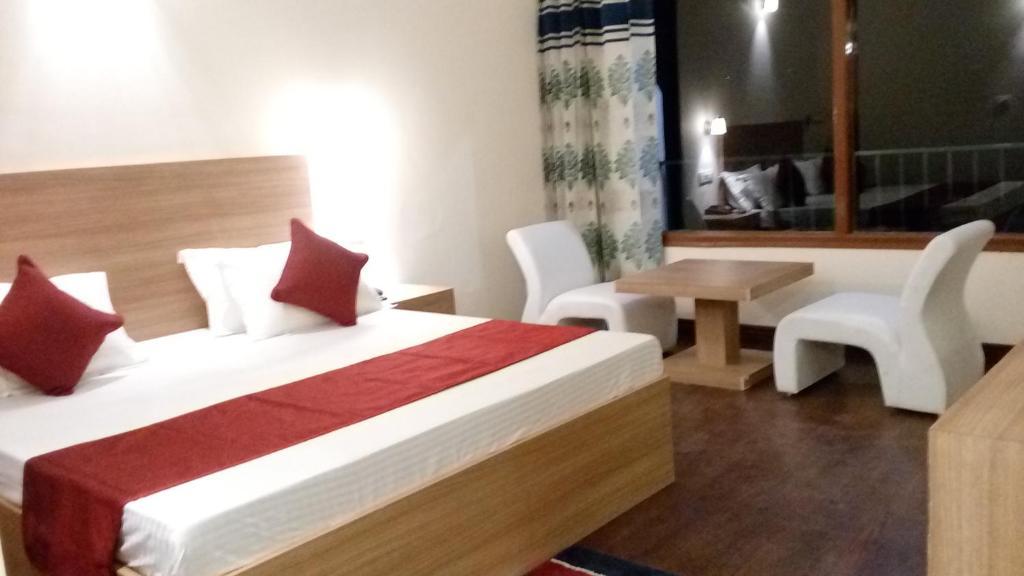 a bedroom with a large bed and a table at hotel emerald valley in Chail hotel_Image