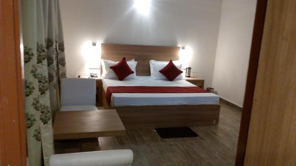 a bedroom with a large bed and a table at hotel emerald valley in Chail hotel_Image