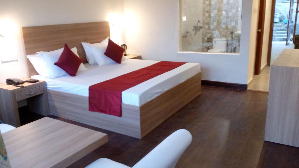 a bedroom with a large bed and a table at hotel emerald valley in Chail hotel_Image