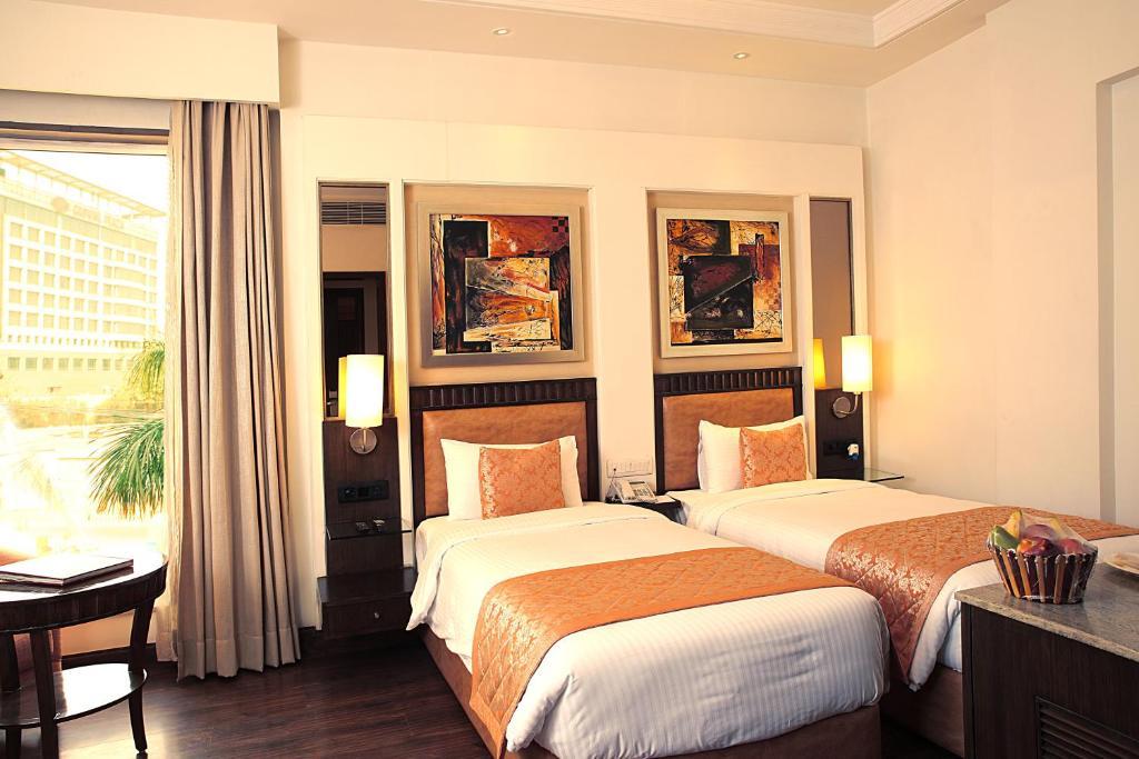 a bedroom with two single bed and a table at inde hotel signature tower in gurugram hotel_Image