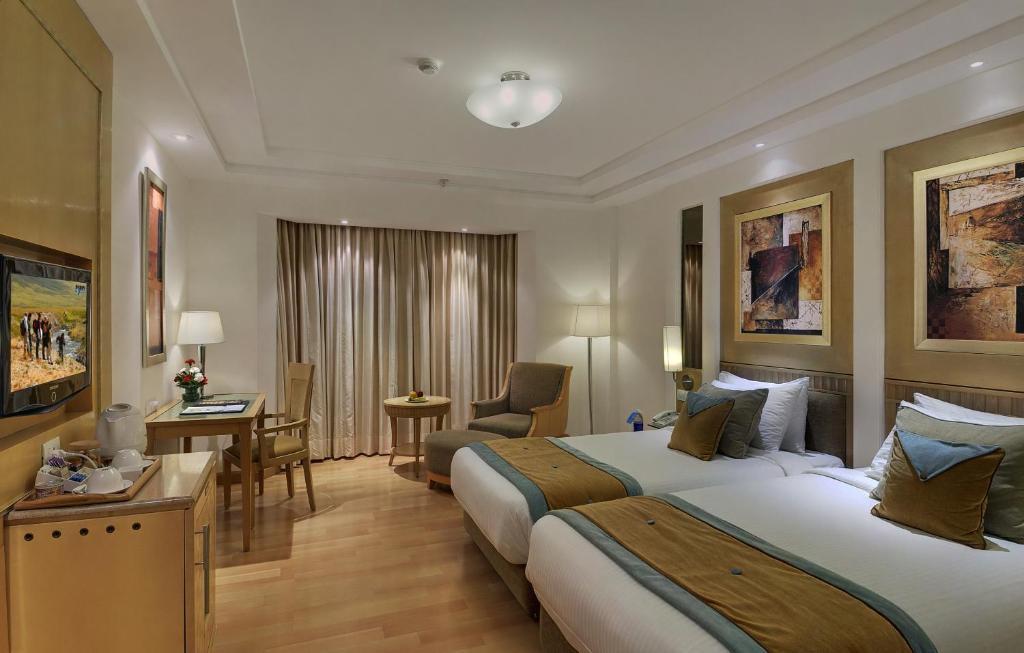 a bedroom with two single bed and a tv at staybook Inde hotel vista woods in Gurugram hotel_Image