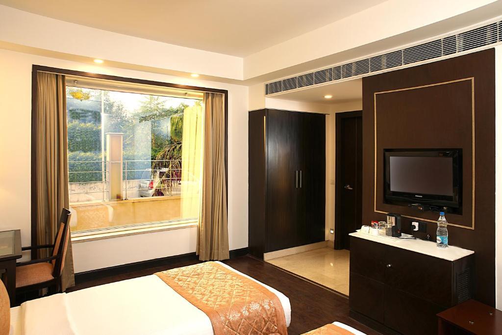 a bedroom with a large bed and a tv at staybook Inde hotel vista woods in Gurugram hotel_Image