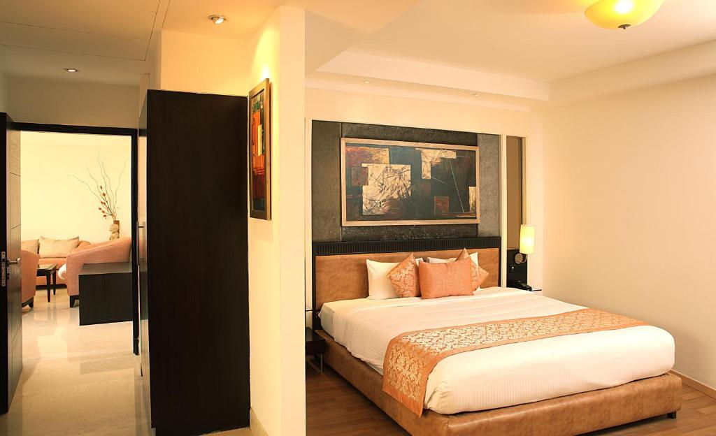 a bedroom with a large bed and wooden door at staybook Inde hotel vista woods in Gurugram hotel_Image