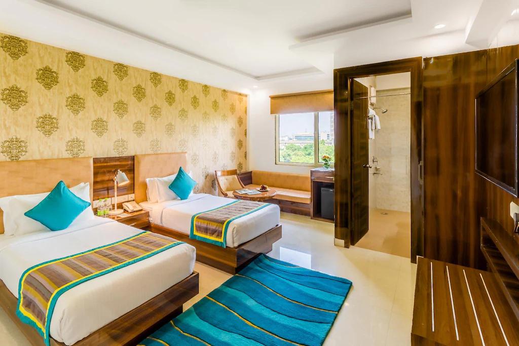 a bedroom with two single bed and sofa at staybook inde hotel cyber city in Gurugram hotel_Image