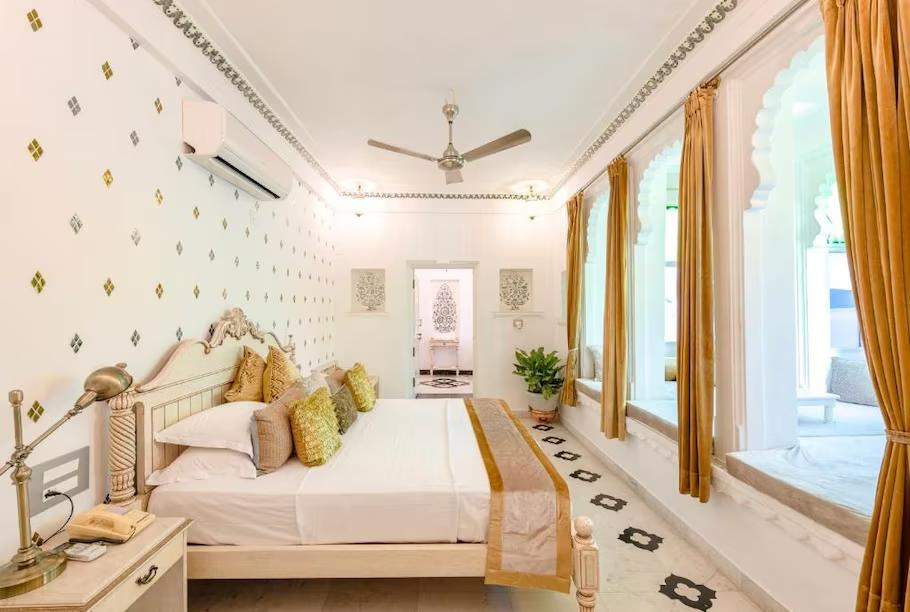 a bedroom with a large bed and a fan at staybook jagat niwas palaca hotel in udaipur hotel_Image