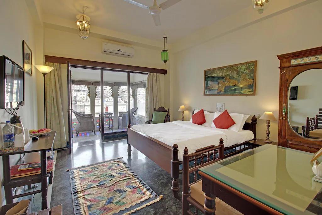 a bedroom with a large bed and a table at lake pichola hotel in udaipur hotel_Image