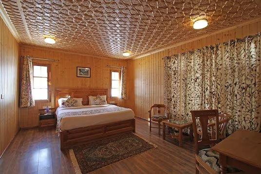 a bedroom with a large bed and chairs at shaw inn by stay pattern in gulmarg hotel_Image