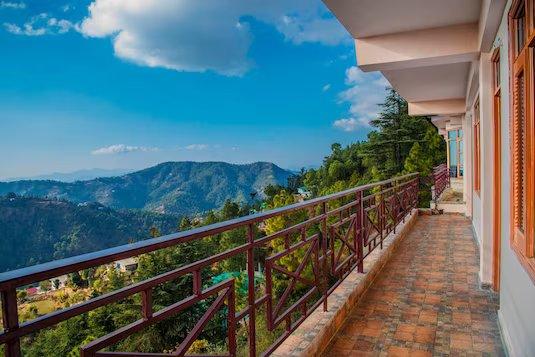 a balcony with a view of the mountains at shimla nature ville in shimla hotel_Image