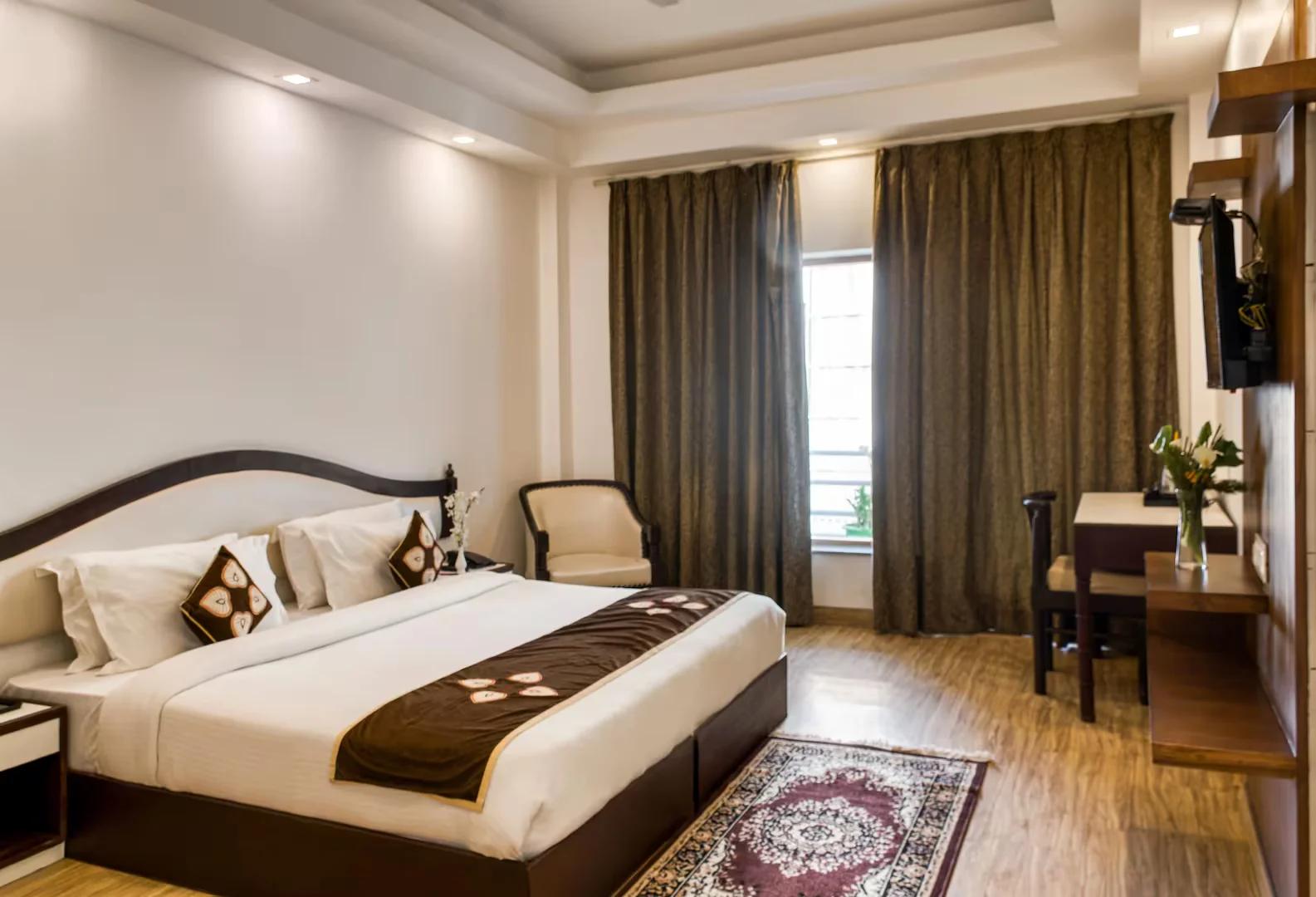 a bedroom with a large bed and a tv at hotel shivalik hills in Mussoorie hotel_Image