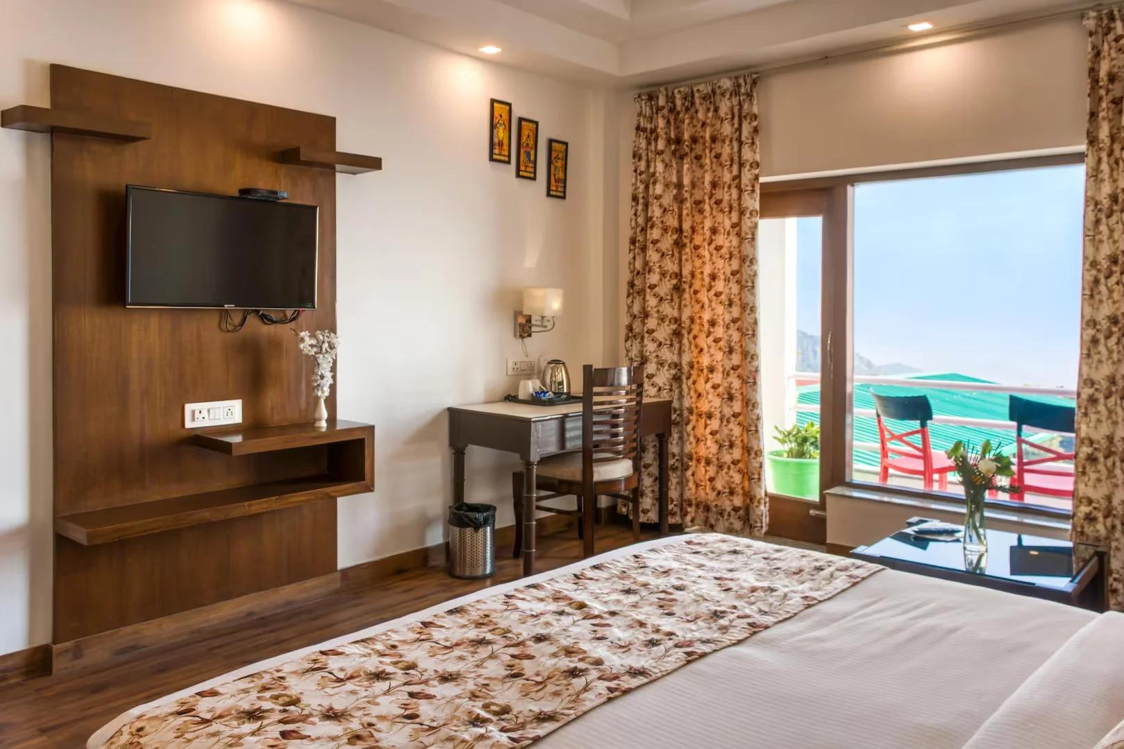 a bedroom with a large bed and a tv at hotel shivalik hills in Mussoorie hotel_Image