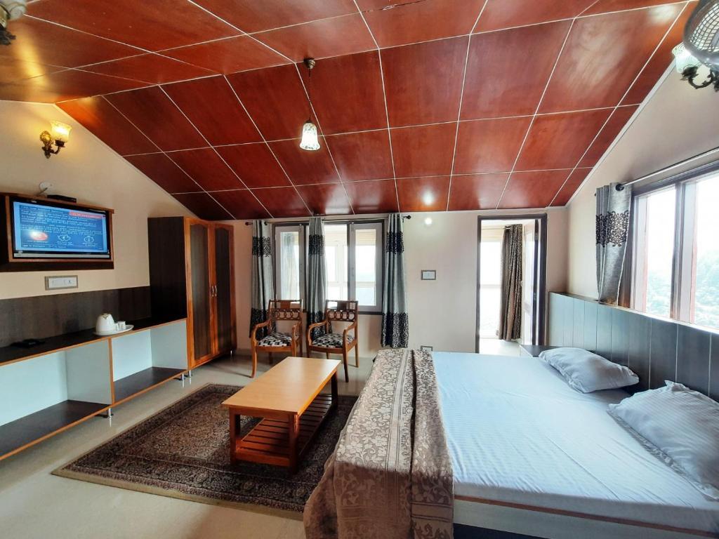 a bedroom with a large bed and a tv at sunrise villa in shimla hotel_Image