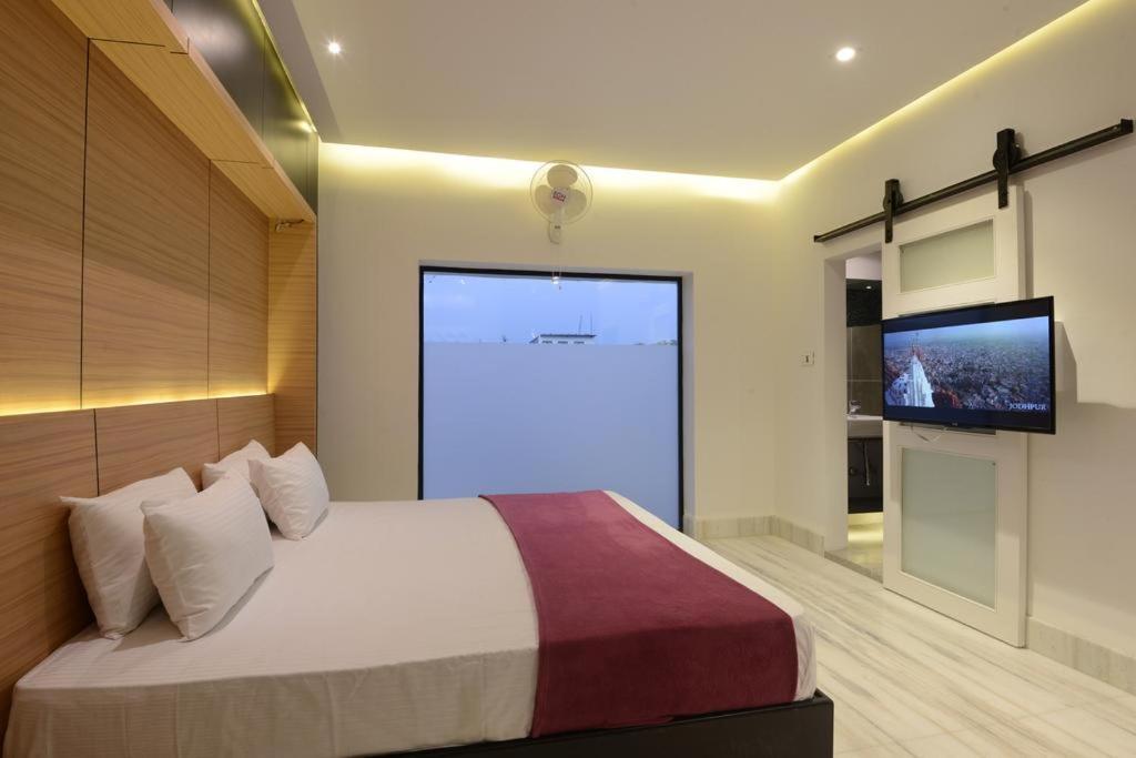a bedroom with a large bed and four pillows & tv at thc backpackers in jodhpur hotel_Image