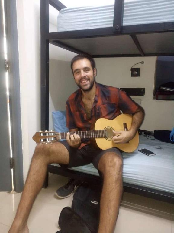 a man with guitar on bed at thc backpackers in jodhpur hotel_Image