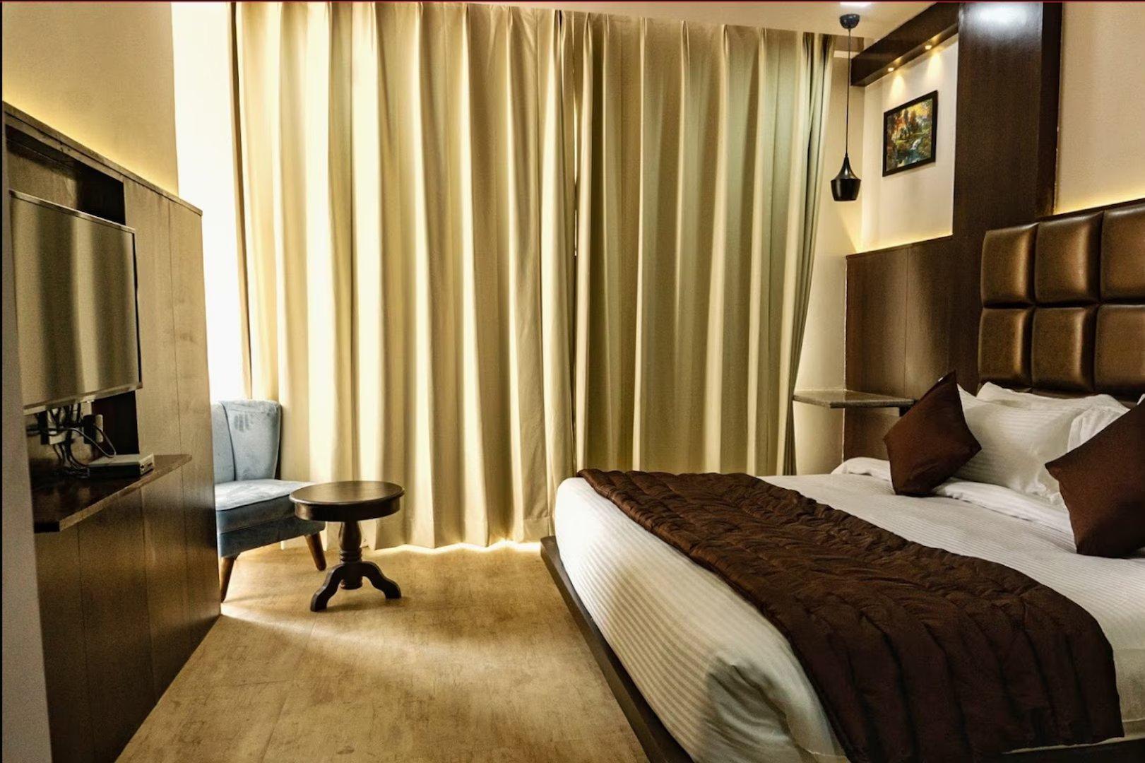 a bedroom with a large bed and a chair at the raas mahal hotel in jaipur hotel_Image