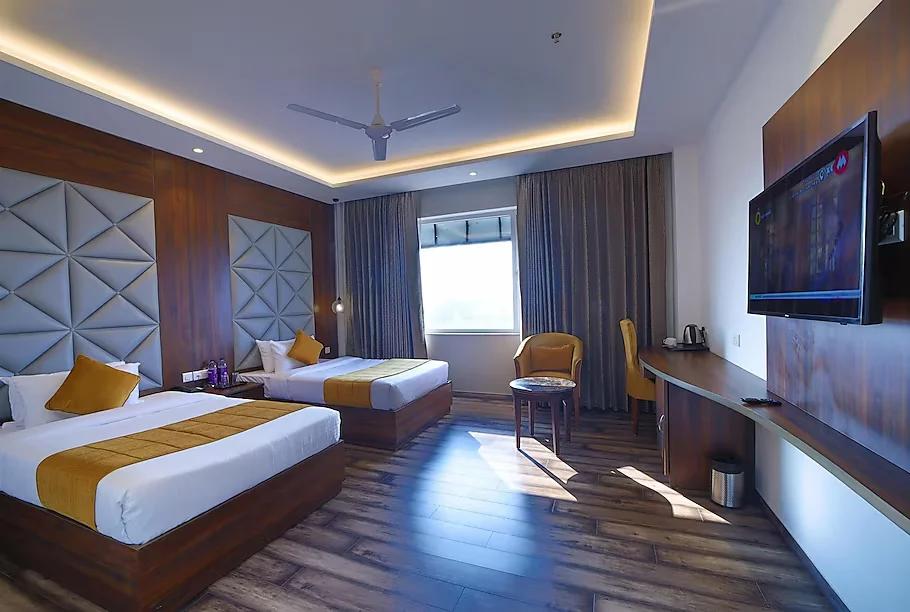 a hotel double bedroom with sofa and a tv and a large window at the Vilana luxurious hotel in rishikesh hotel_Image