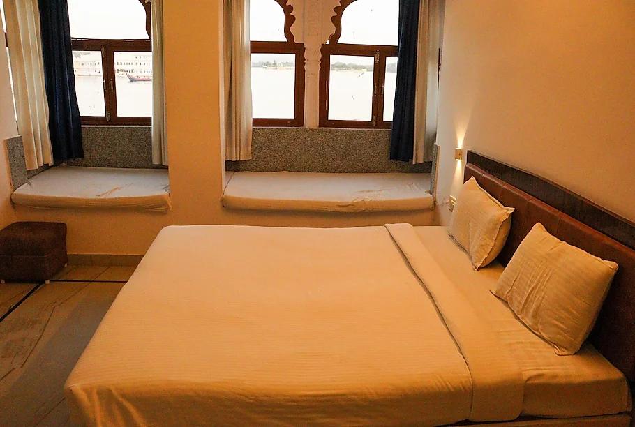 a bedroom with a large bed and window view at lakeside in uadaipur hotel_Image