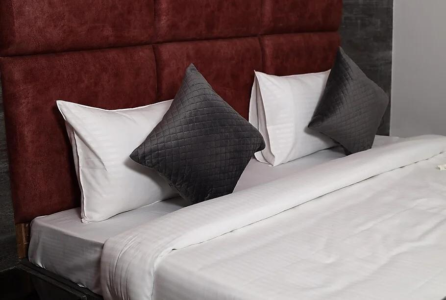 a bed with four pillows on top of it at thor hotel in agra hotel_Image